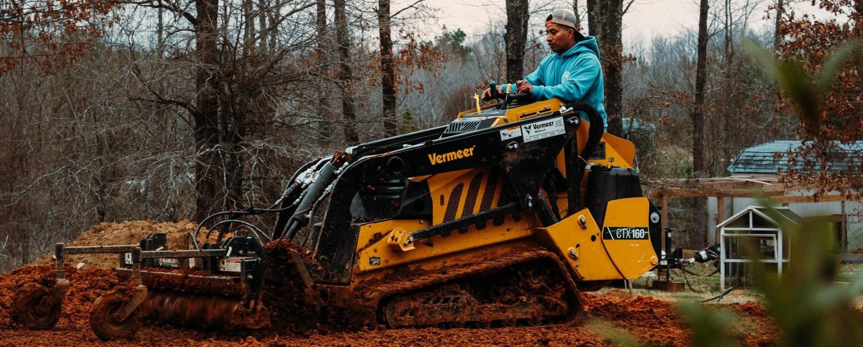 Landscape crew member preparing soil with compact equipment