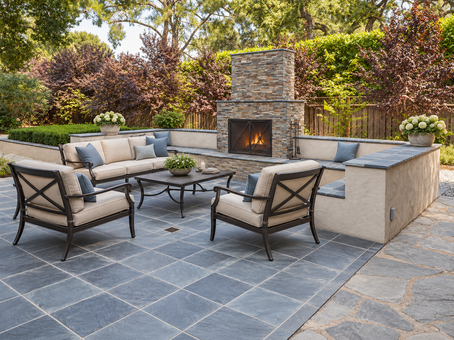 Natural stone patio with an outdoor fireplace, built-in seating walls, and cushioned lounge furniture.