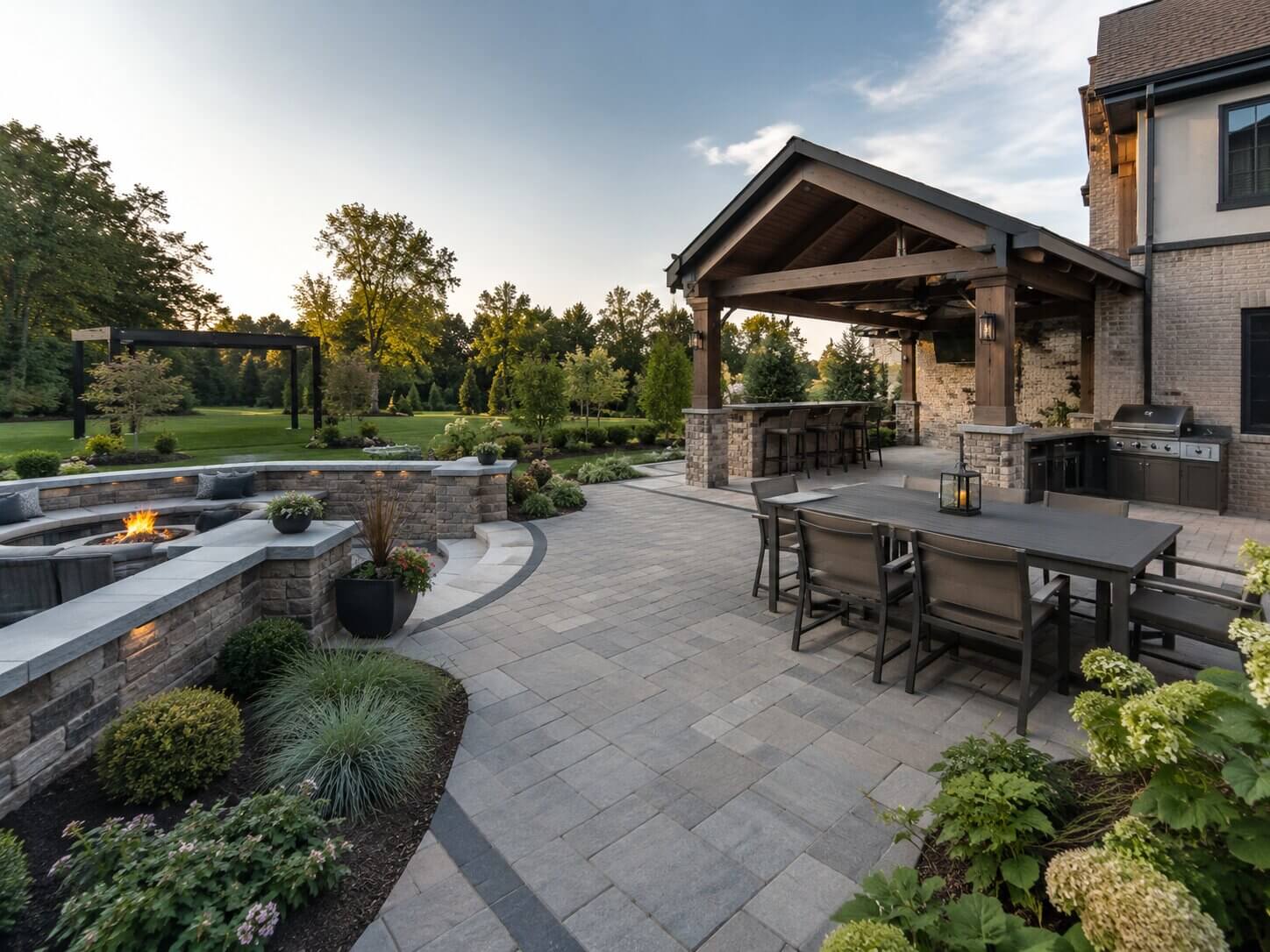 Outdoor living patio with pergola, stone seating, fire feature, and landscape beds